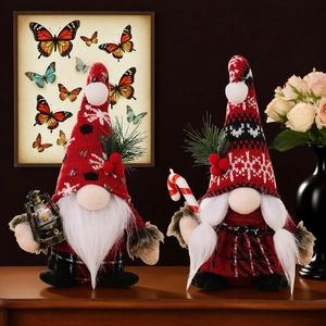 Christmas gnomes set with red hats holding lantern and candy cane on wooden table