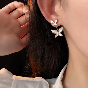 Détail de boucles d'oreilles papillon en émail blanc superposé avec placage en or