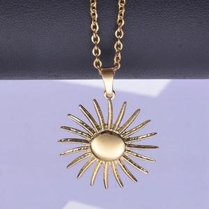 Close-up of golden sun pendant necklace with radiant rays on a polished metal surface
