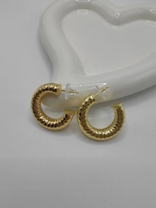 Detailed close-up of chunky gold-plated C-shaped earrings with diamond-cut texture