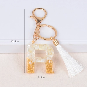 Detail of R-letter keychain with resin gold foil and white tassel, 10.5cm height size