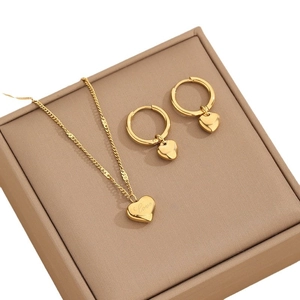 Polished gold heart jewelry set with necklace and earrings on a gift box background