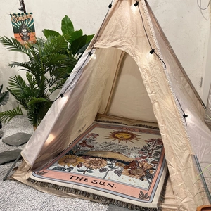 Detail of bohemian Sun Tarot woven cotton blanket with fringe edges inside a camping tent