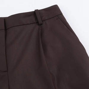 Détails du pantalon plissé à taille haute montrant la ceinture et les poches marron