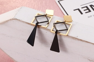 Detail of geometric titanium earrings with black triangle and gold square pendants