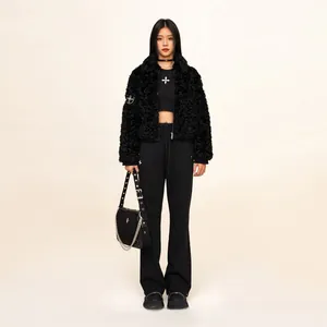 Full view of model wearing black faux fur jacket and cross pattern crop top with trousers