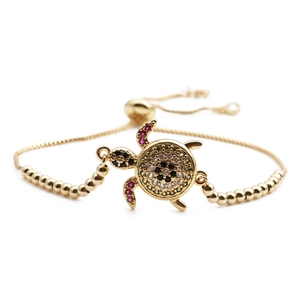 Adjustable golden sea turtle bracelet with colorful zircons on a white background