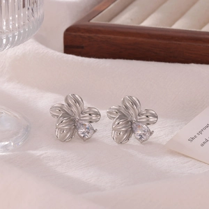 Silver flower stud earrings with teardrop zircon on white textured background