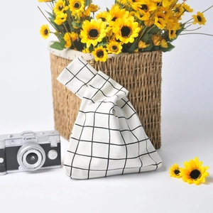 Detail of black and white checkered canvas knot bag with asymmetrical handles and floral decor
