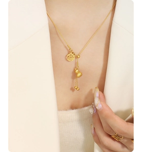 Detail of gold gourd necklace with Fu character pendant and tassel on model