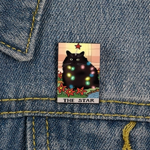 Tarot Cat enamel pin featuring The Star design with a black cat and fairy lights on denim