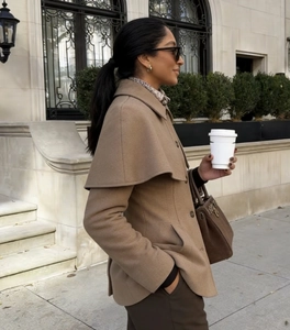 Detail of camel wool cape coat featuring oversized collar and premium button accents