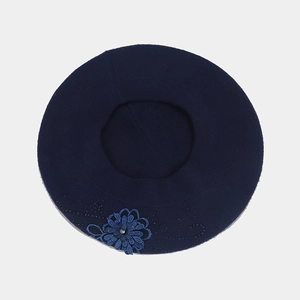 Dettaglio del basco in lana blu navy con fiore in pizzo e strass di cristallo lucido