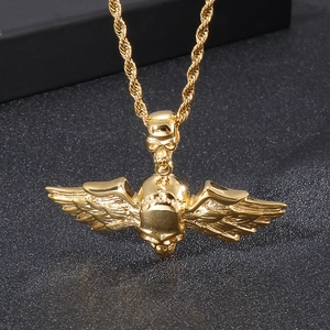Détail d'un pendentif tête de mort doré avec ailes d'ange sur une chaîne torsadée