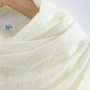 Detailed close-up of off-white crinkled cotton scarf texture and soft fabric fibers
