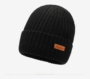 Close-up of black ribbed knit beanie with orange leather patch and warm fleece lining