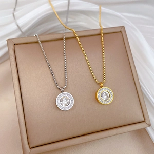 Detail of gold and silver titanium steel necklaces with crystal circle pendants on a box