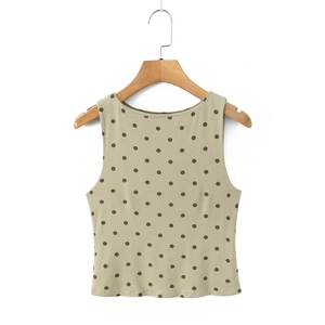 Détail d'un haut sans manches beige avec des pois marrons suspendu sur un cintre en bois