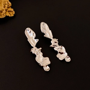 Vue macro de boucles d'oreilles argentées en métal liquide irrégulier au fini poli