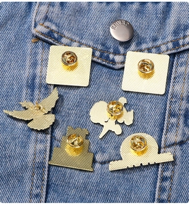 Macro view of gold metal pin backings with butterfly clasps on blue denim fabric