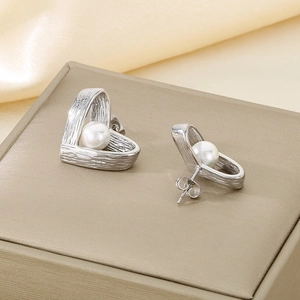 Macro detail of French vintage heart-shaped stud earrings with brushed metal and pearl