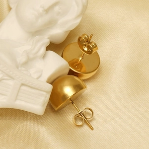 Polished gold stainless steel dome earrings displayed on elegant champagne satin fabric