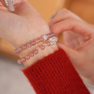 Detail of pink strawberry quartz beaded bracelets with a silver crown charm on a wrist