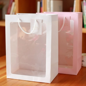 Détail d'un sac cadeau en papier avec grande fenêtre transparente et carte de remerciement