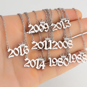 Silver crown year pendant necklace in stainless steel shown on a hand for scale