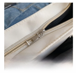 Macro shot of smooth silver metal zipper and black lining on cream canvas crossbody bag
