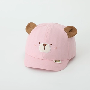 Détail d'une casquette rose en coton pour bébé avec oreilles d'ours et broderie visage