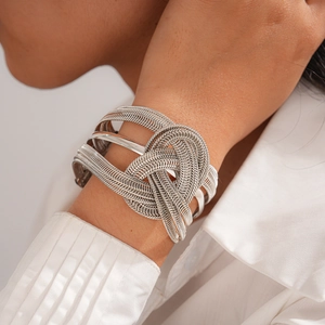 Macro shot of silver metal woven knot cuff bangle showing detailed texture and modern design