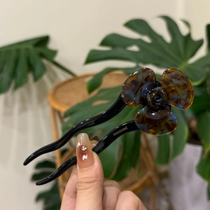 Close-up of a tortoiseshell acetate flower hair stick with a sleek black handle