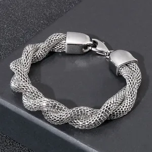 Detailed view of silver twisted mesh chain bracelet with lobster clasp on dark texture