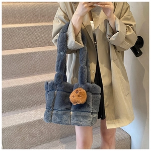 Blue faux fur tote bag with brown bear charm shown on model in a stylish winter scene