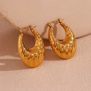 Close-up of gold plated stainless steel hollow oval earrings with geometric relief texture