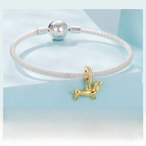 Macro shot of gold dachshund charm and zircon spacer on woven mesh silver bracelet