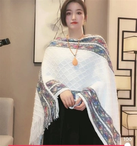 Detail of white knit poncho featuring colorful stripes and bohemian fringe tassels
