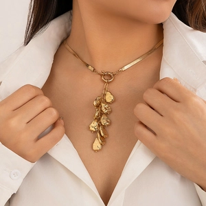 Close-up of gold snake chain necklace with irregular layered metallic pendants on a model