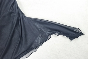 Vue détaillée du tissu en maille transparente noire avec bordure ondulée délicate