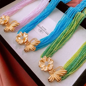 Détail macro de chaînes de taille perlées multicouches avec fermoirs fleurs et papillons