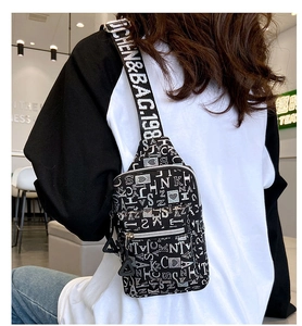 Back view of a casual canvas chest bag with white letter prints and adjustable shoulder strap