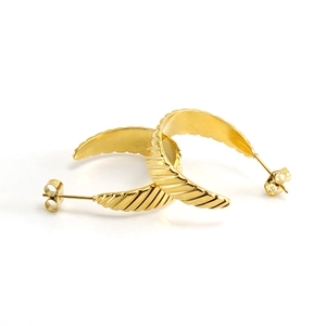 Detail of golden C-shaped stainless steel earrings with textured diagonal spiral patterns