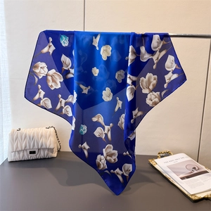 Gros plan d'un élégant foulard en soie bleu foncé avec motif floral et bords roulottés