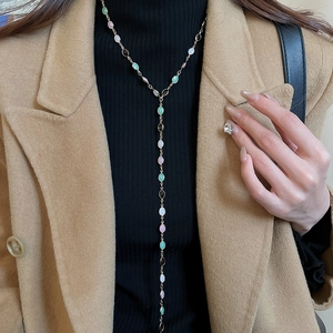 Detail of colorful resin gemstones on a gold-tone necklace worn by a fashion model