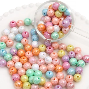 Close-up of colorful pearlescent acrylic beads pouring into a white textured plate