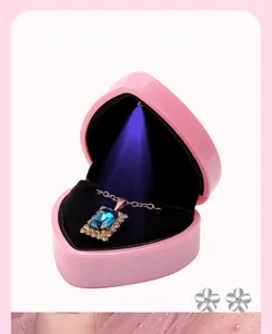 Detail of pink heart jewelry box with LED light reflecting on blue gemstone pendant