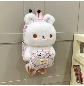 Plush white bunny backpack with pink wavy pocket details hanging on a door handle