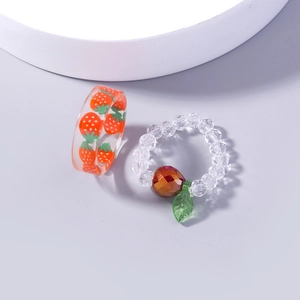 Close-up of transparent resin strawberry rings with red fruit charms and green leaves
