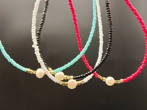 Macro detail of multi-colored seed beads and white freshwater pearls on a necklace